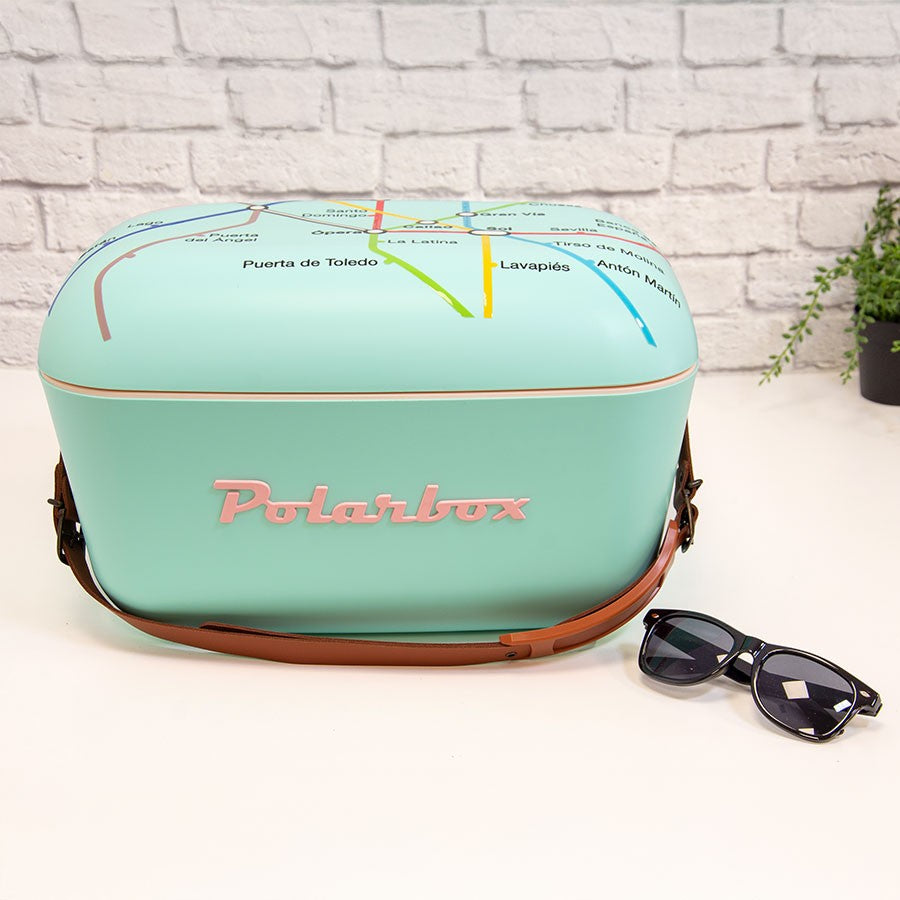 Nevera Polarbox azul turquesa con diseño de mapa y gafas de sol sobre mesa blanca