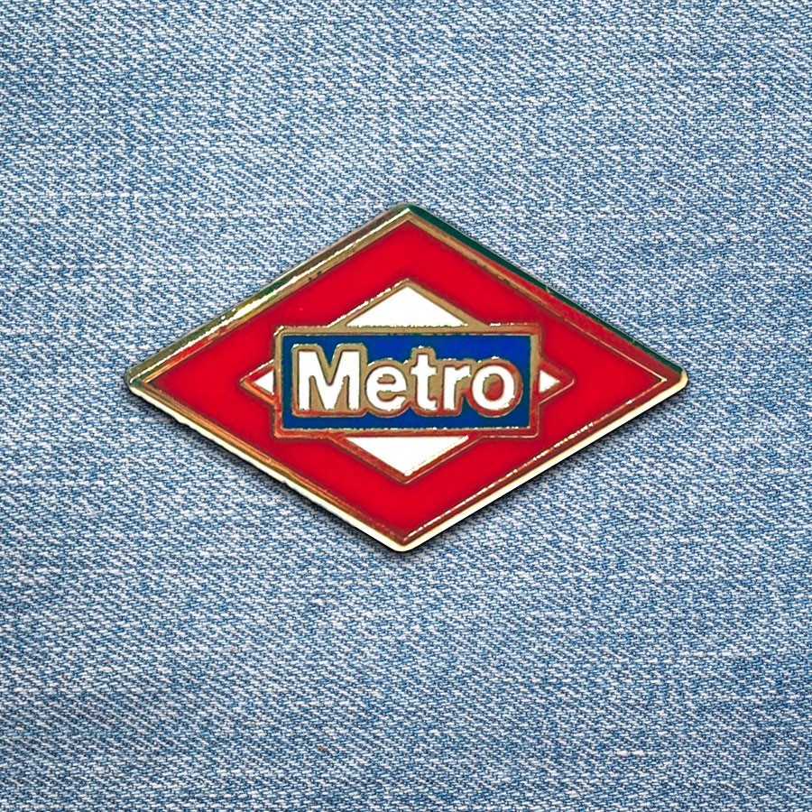 Pin del logo Metro de Madrid sobre tela vaquera azul, distintivo transporte público