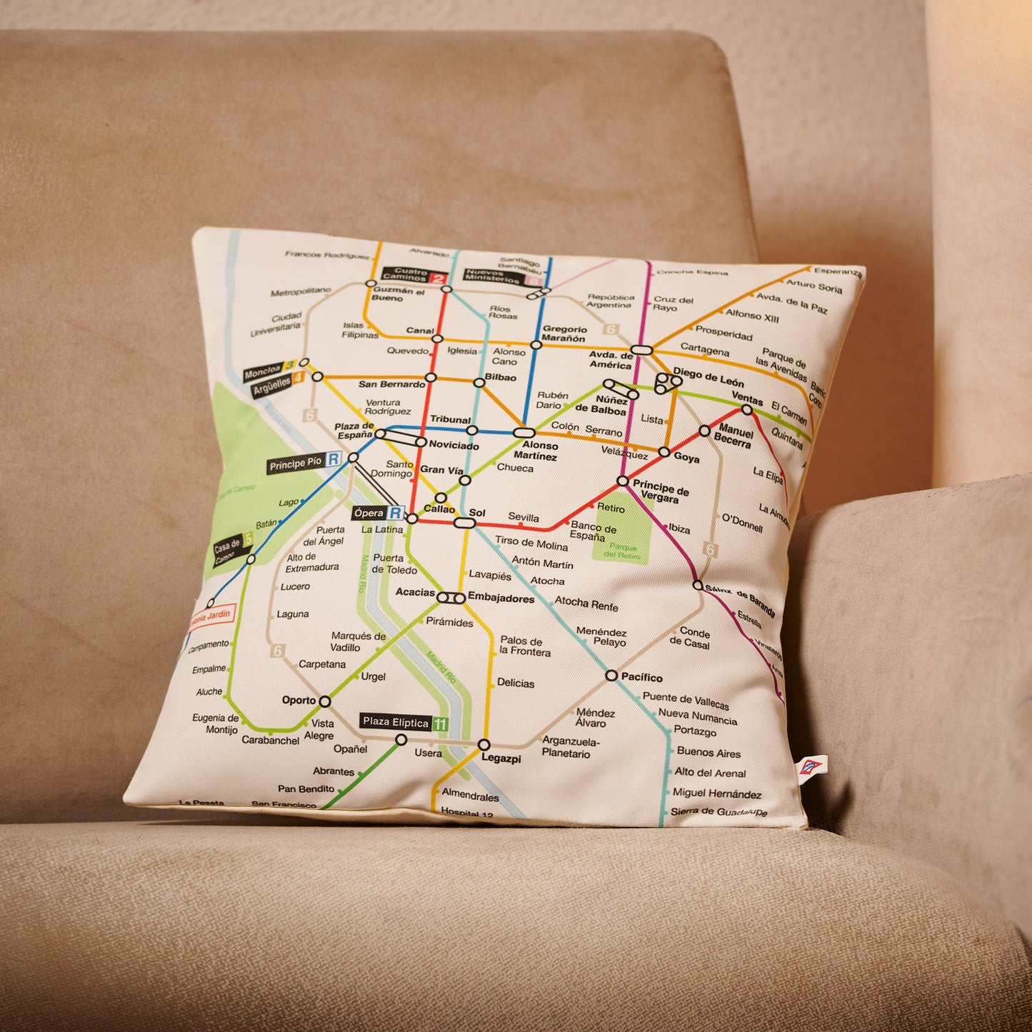 Cojín decorativo con diseño de mapa del metro de Madrid sobre sofá beige