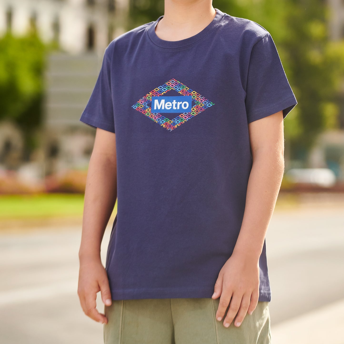 Niño con camiseta azul con logo Metro y diseño geométrico, al aire libre