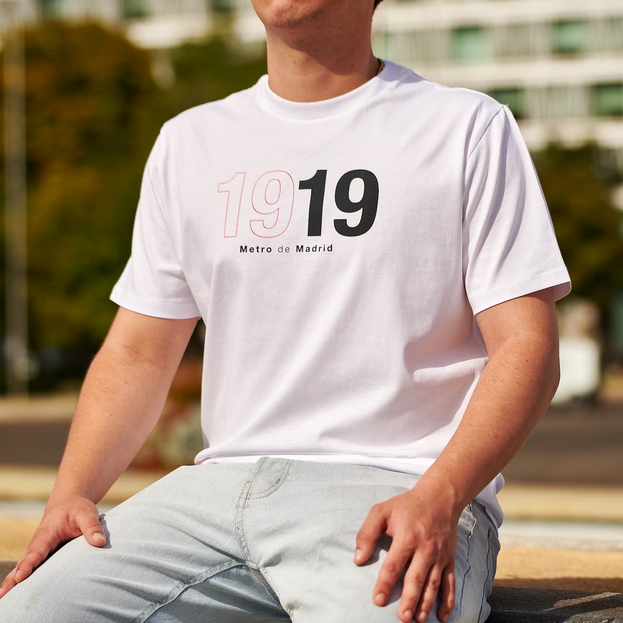 Hombre con camiseta blanca Metro de Madrid 1919 sentado al aire libre