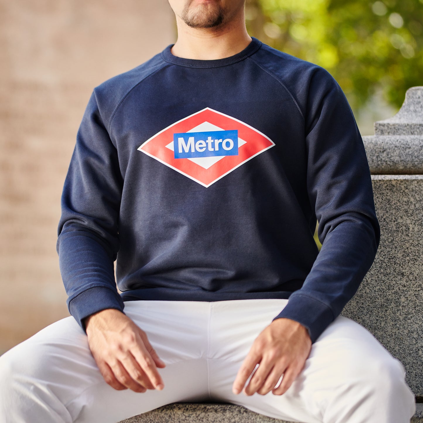 Hombre con sudadera azul de Metro Madrid, sentado al aire libre, moda urbana española