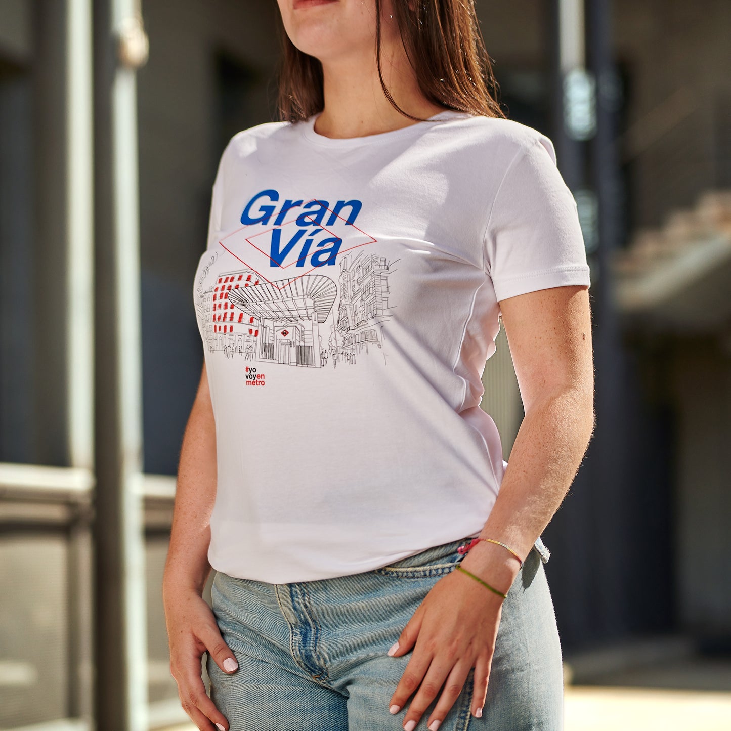 Mujer con camiseta blanca de Gran Vía Madrid y vaqueros en un entorno urbano
