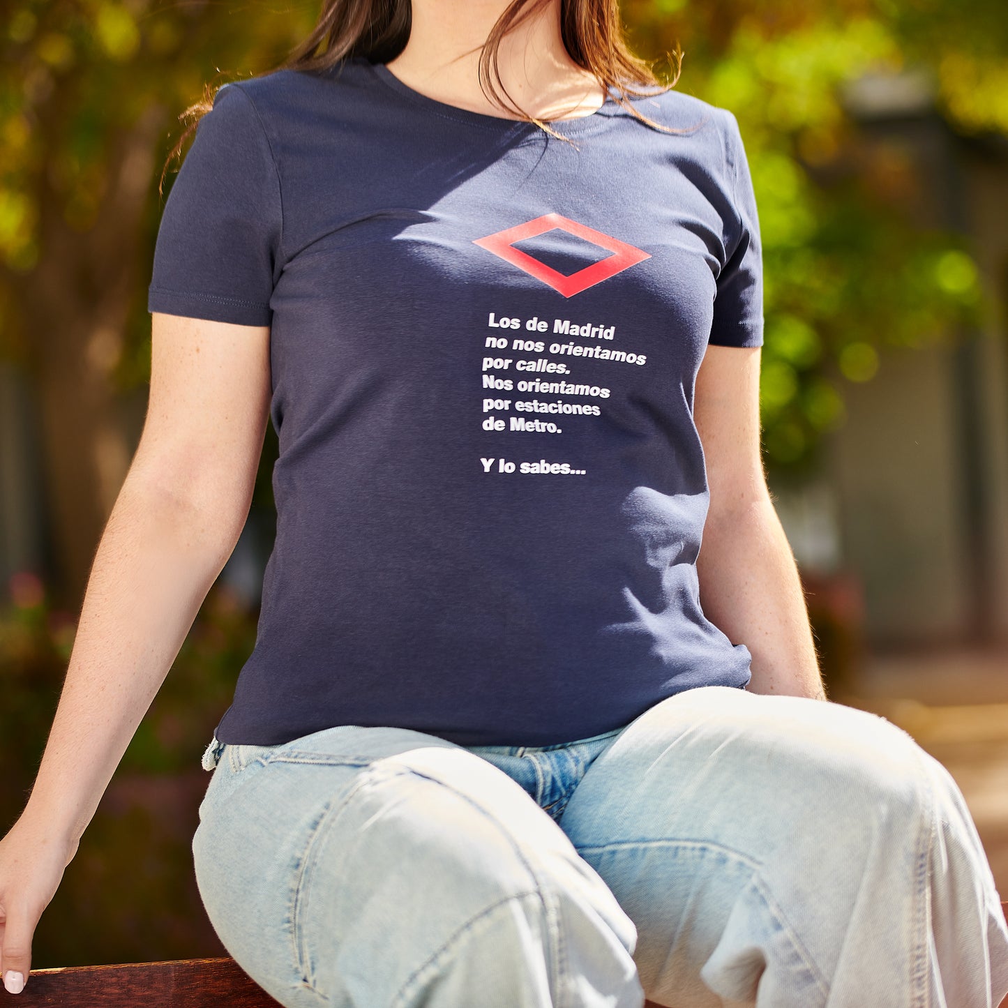 Camiseta azul con texto divertido sobre el Metro de Madrid, mujer sentada al aire libre