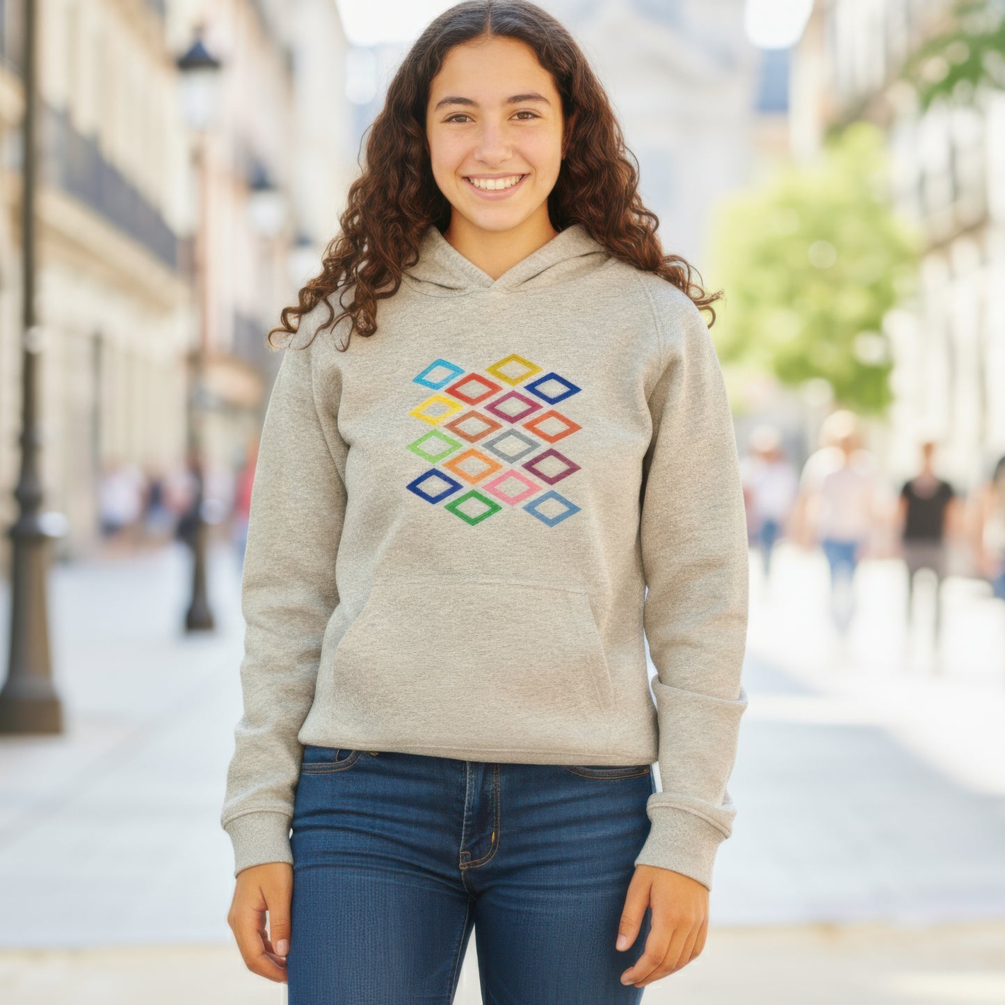Mujer joven con sudadera gris de diamantes coloridos en calle urbana, moda casual