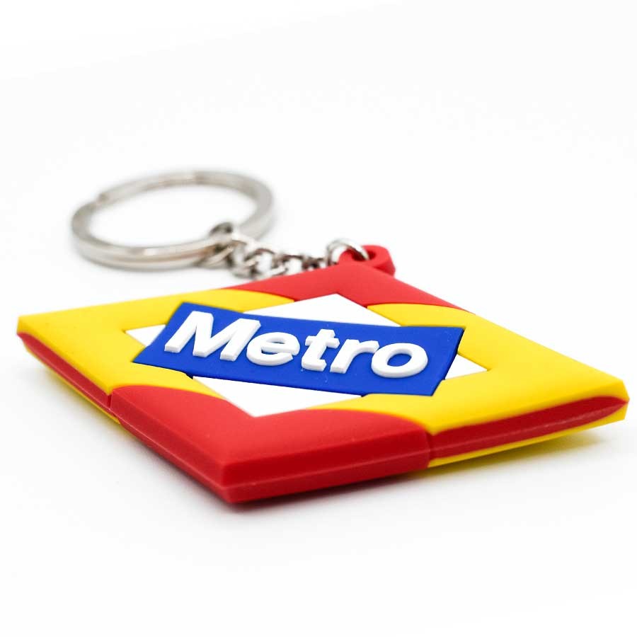 Llavero de goma metro de Madrid con logotipo en colores rojo, amarillo y azul sobre fondo blanco.
