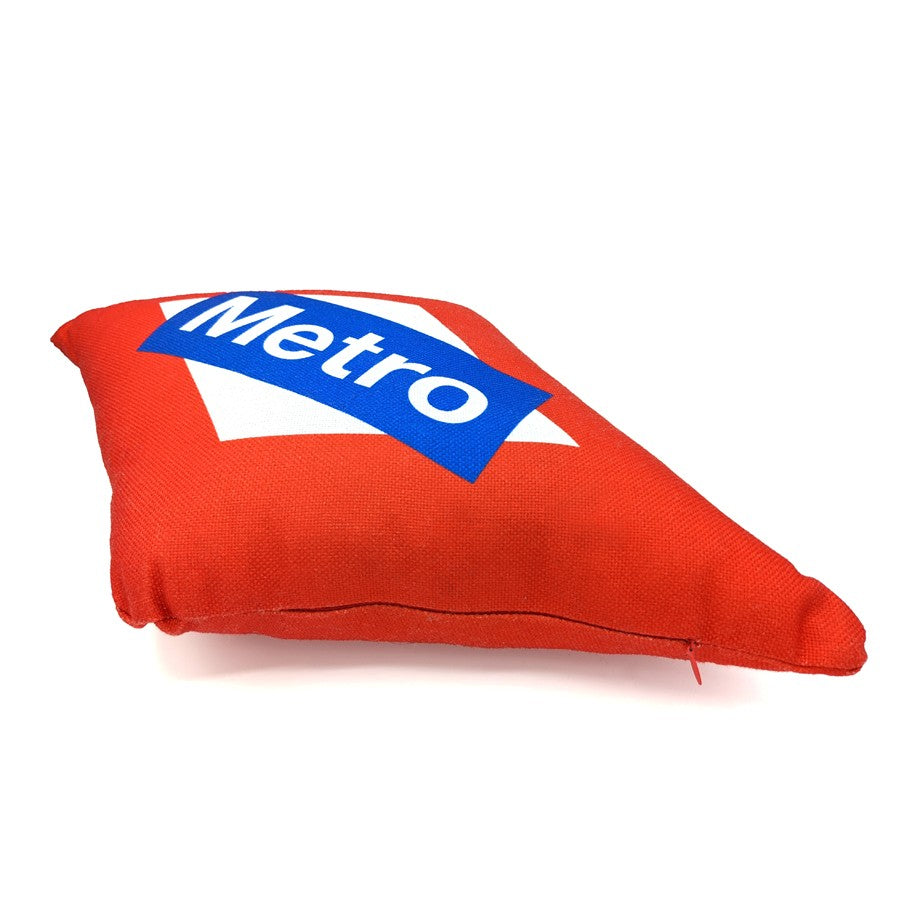 Cojín rojo con diseño de letrero Metro de Madrid sobre fondo blanco