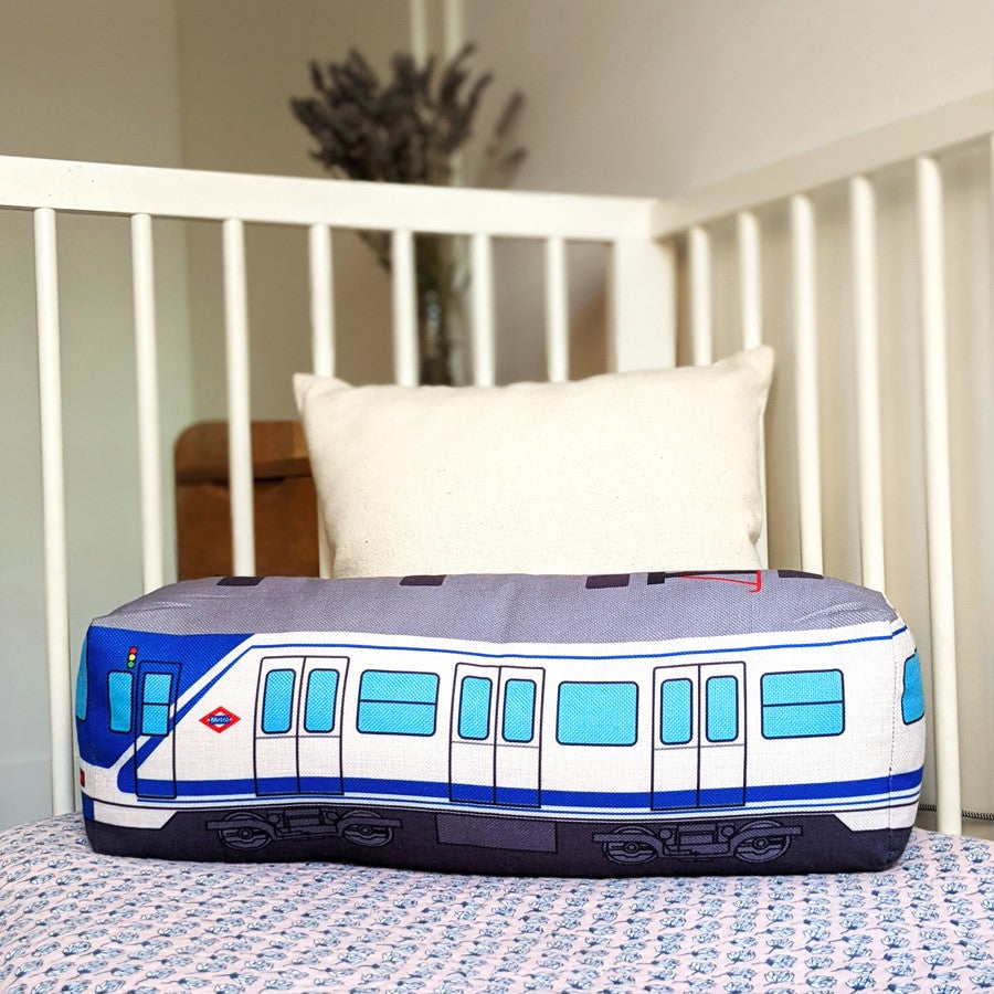 Cojín con diseño de tren metro azul sobre cama infantil, decoración habitación infantil.