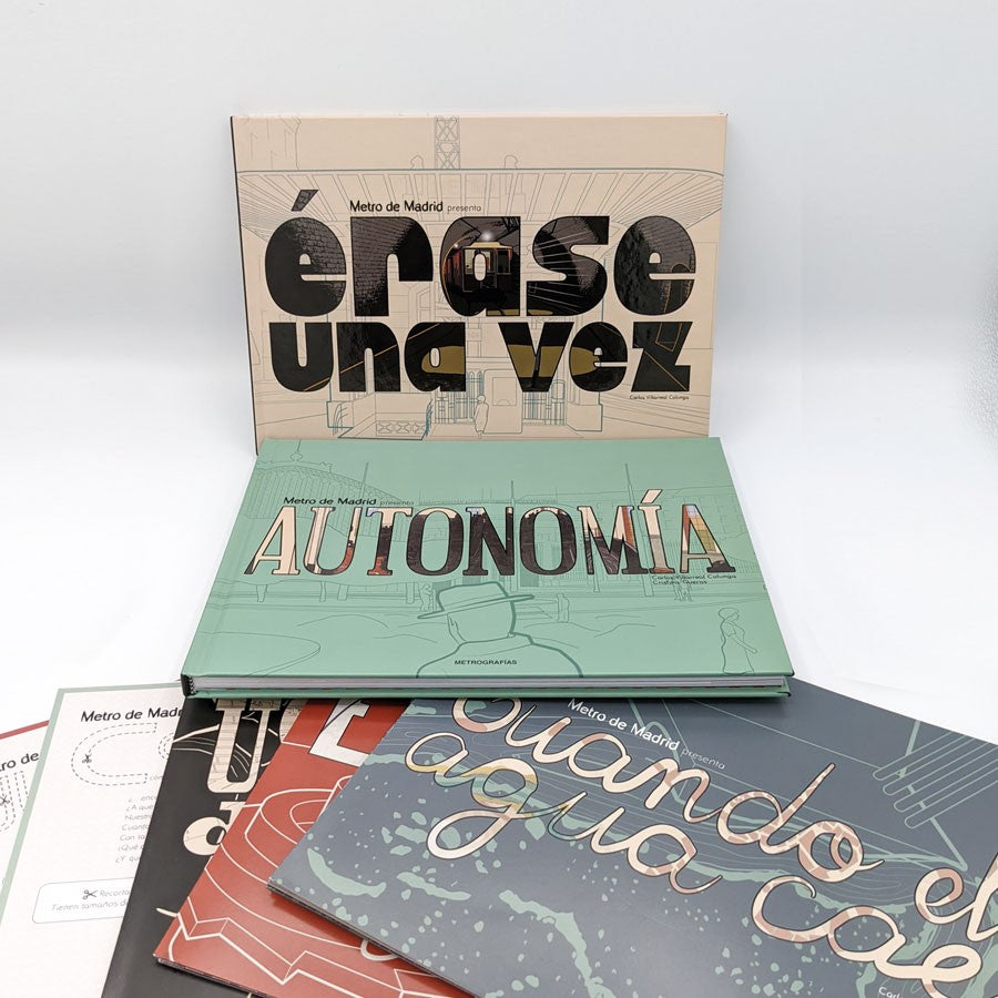 Libros ilustrados de Metro de Madrid apilados, títulos visibles como 'Érase una vez' y 'Autonomía'.