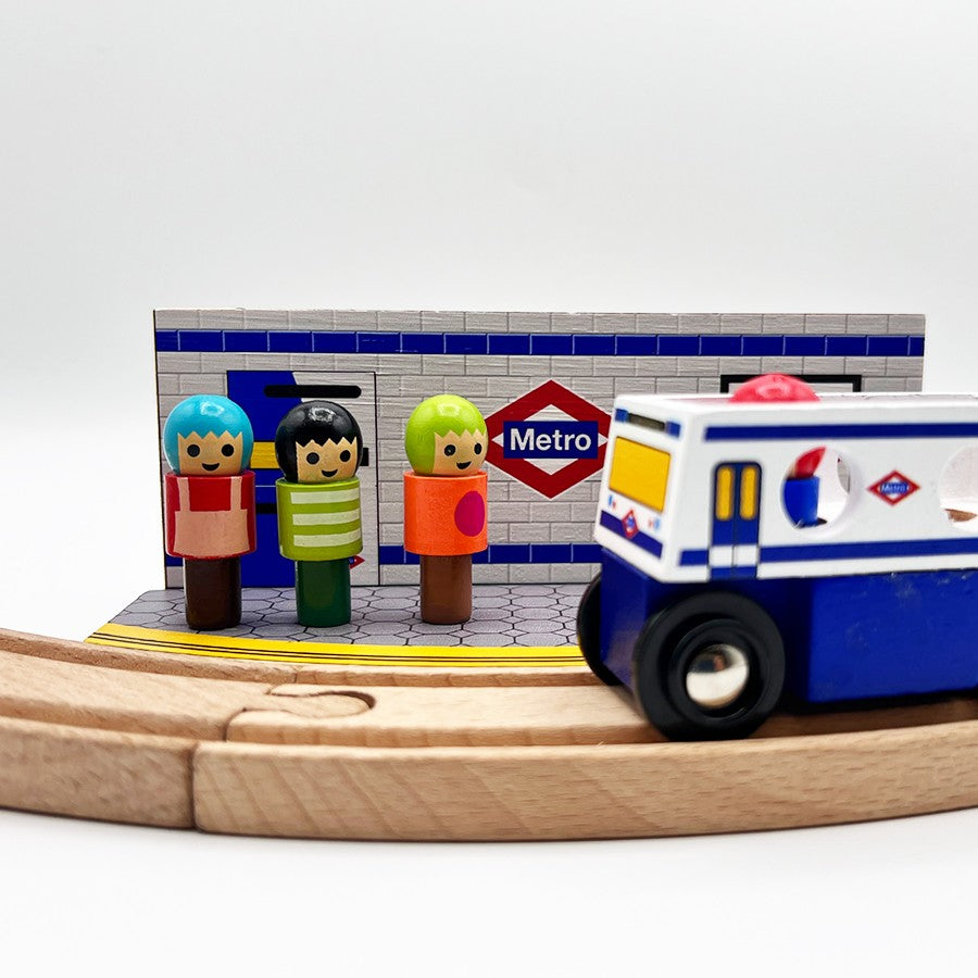 Juguetes de madera de metro y figuras en estación de tren infantil sobre rieles