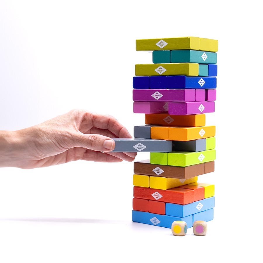 Mano jugando torre de bloques de madera de colores, juego de mesa infantil, fondo blanco