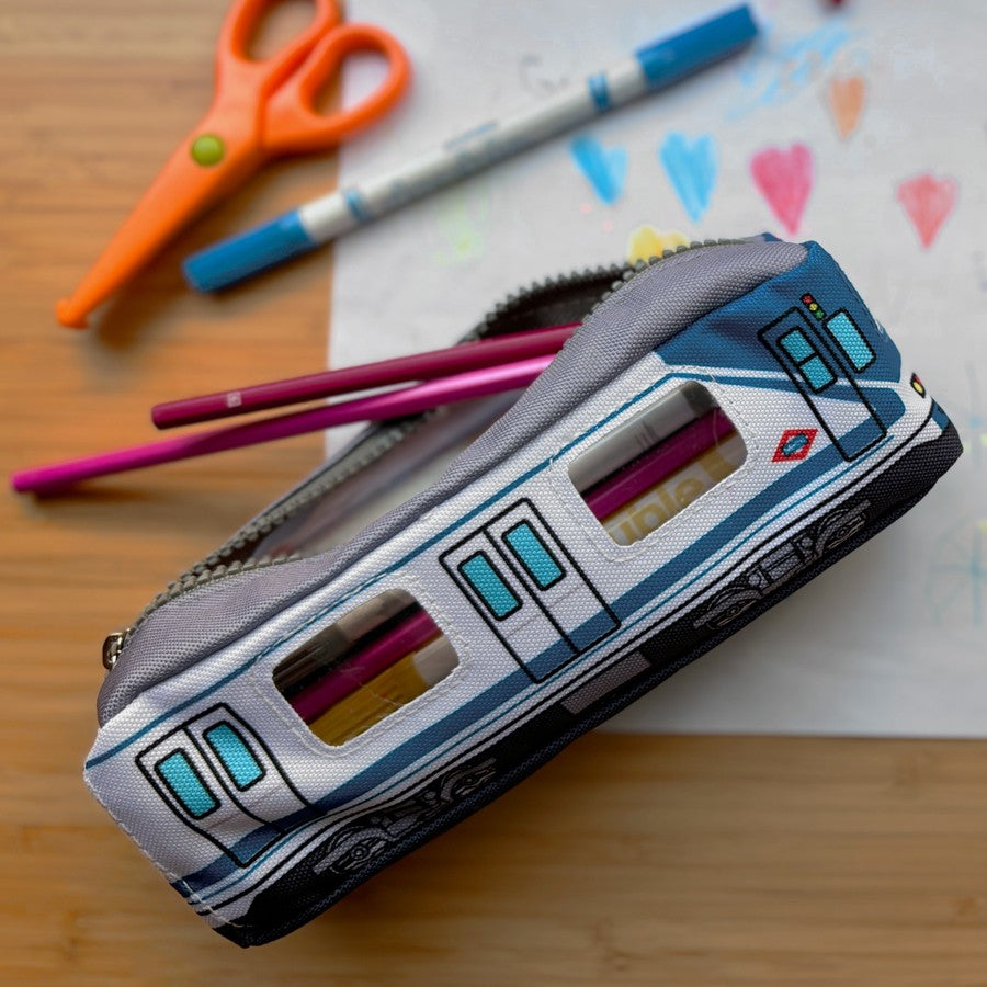 Estuche escolar diseño metro Madrid, lápices, tijeras y dibujo infantil sobre mesa