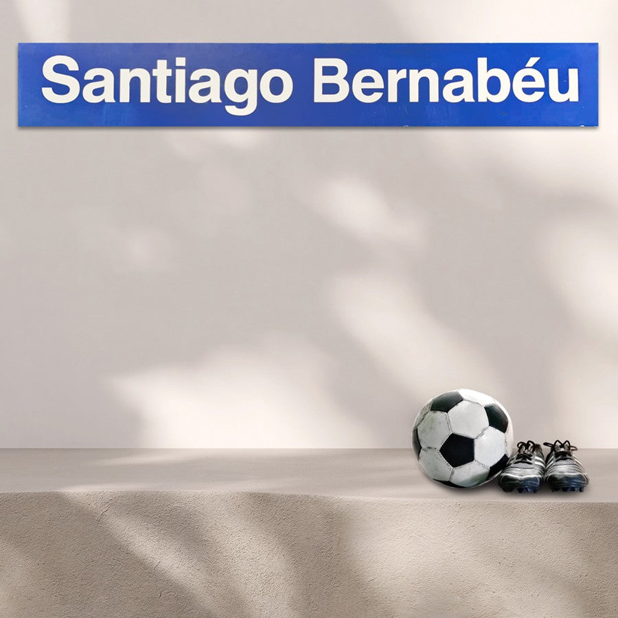 Cartel azul Santiago Bernabéu, balón de fútbol y botines sobre superficie clara