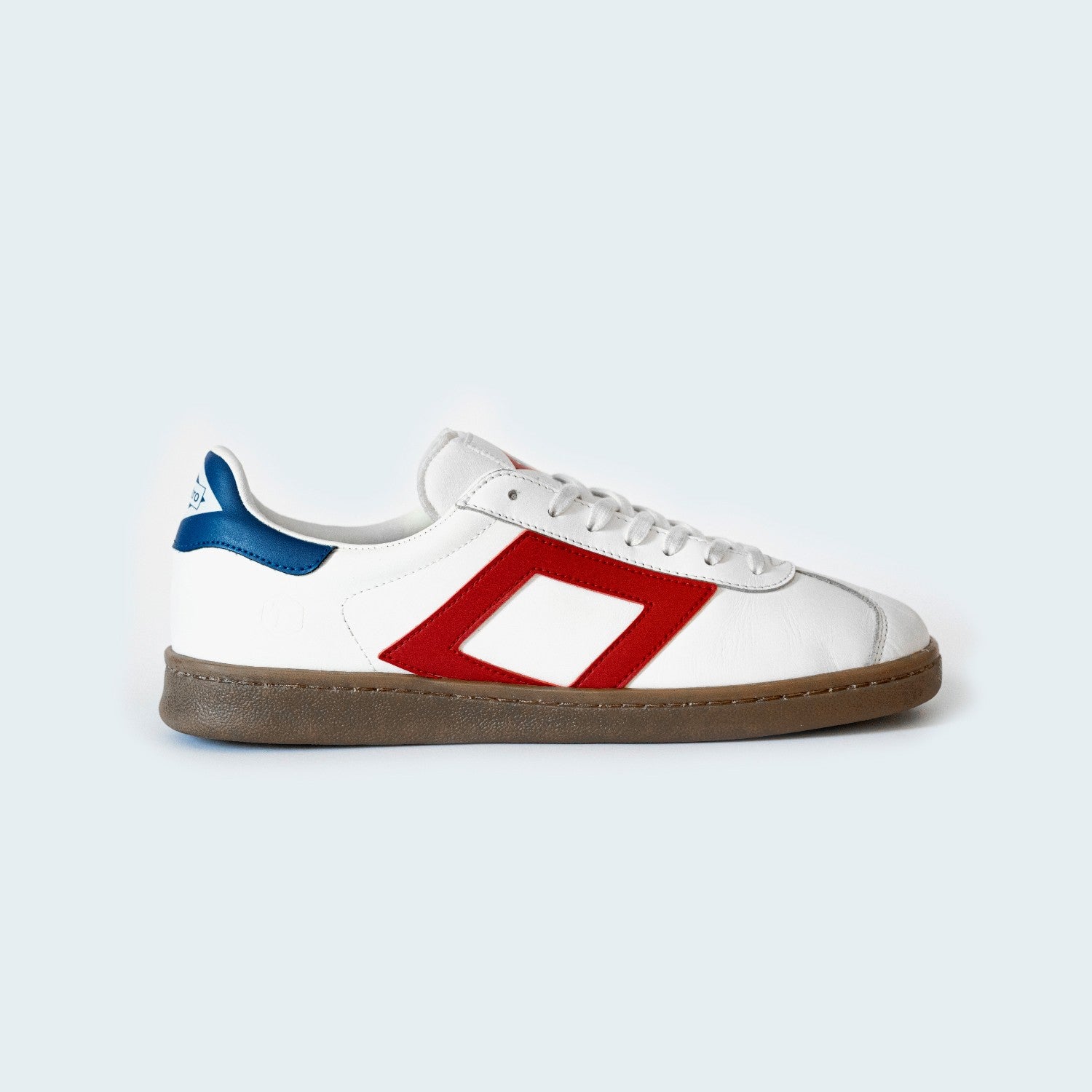 Zapatilla deportiva blanca con logo rojo y talón azul sobre fondo claro