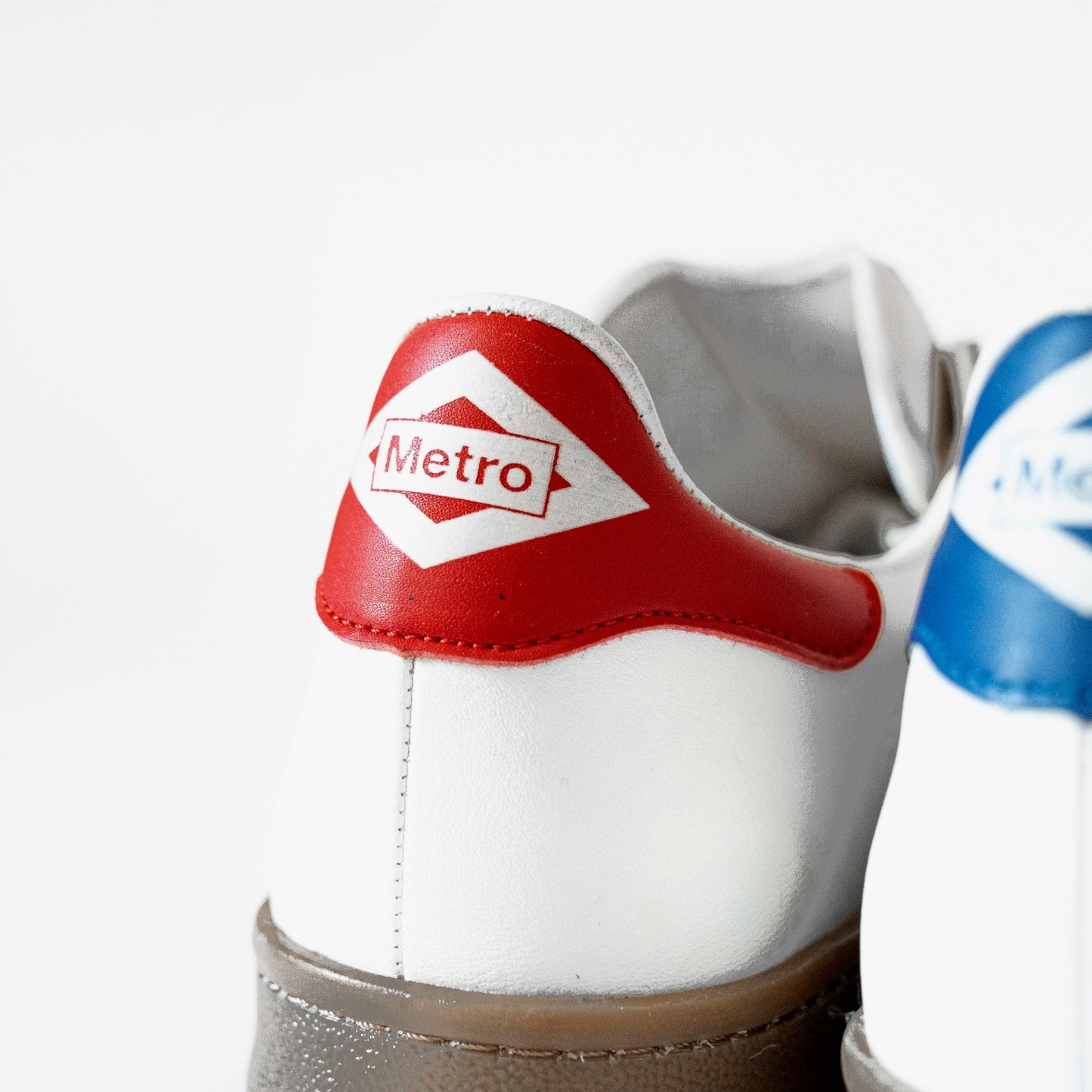 Zapatilla blanca con talón rojo y logo Metro, calzado urbano moderno