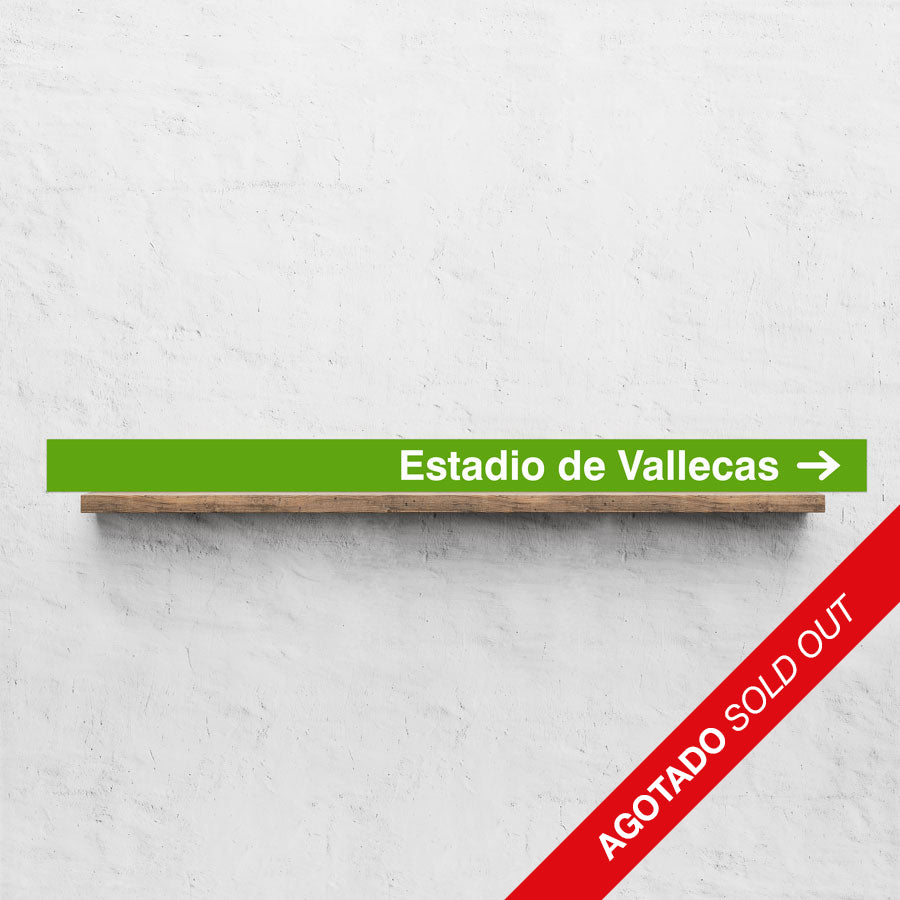Letrero verde Estadio de Vallecas con flecha sobre estante de madera, texto AGOTADO SOLD OUT