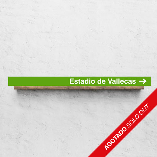 Letrero verde Estadio de Vallecas con flecha sobre estante de madera, texto AGOTADO SOLD OUT