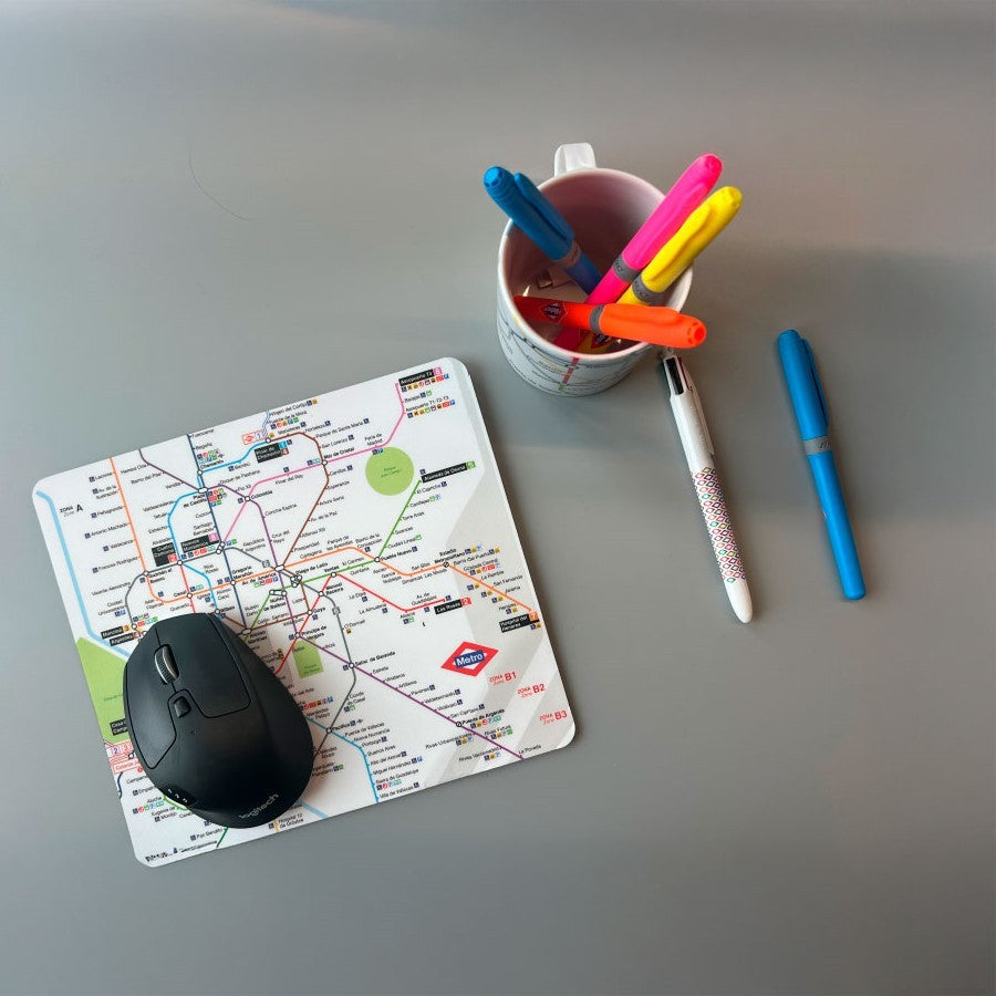 Alfombrilla de ratón con mapa del metro de Madrid, bolígrafos y taza en escritorio gris