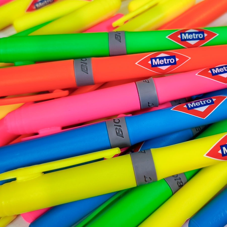 Marcadores fluorescentes BIC coloridos apilados, algunos con logo Metro visible, papelería escolar