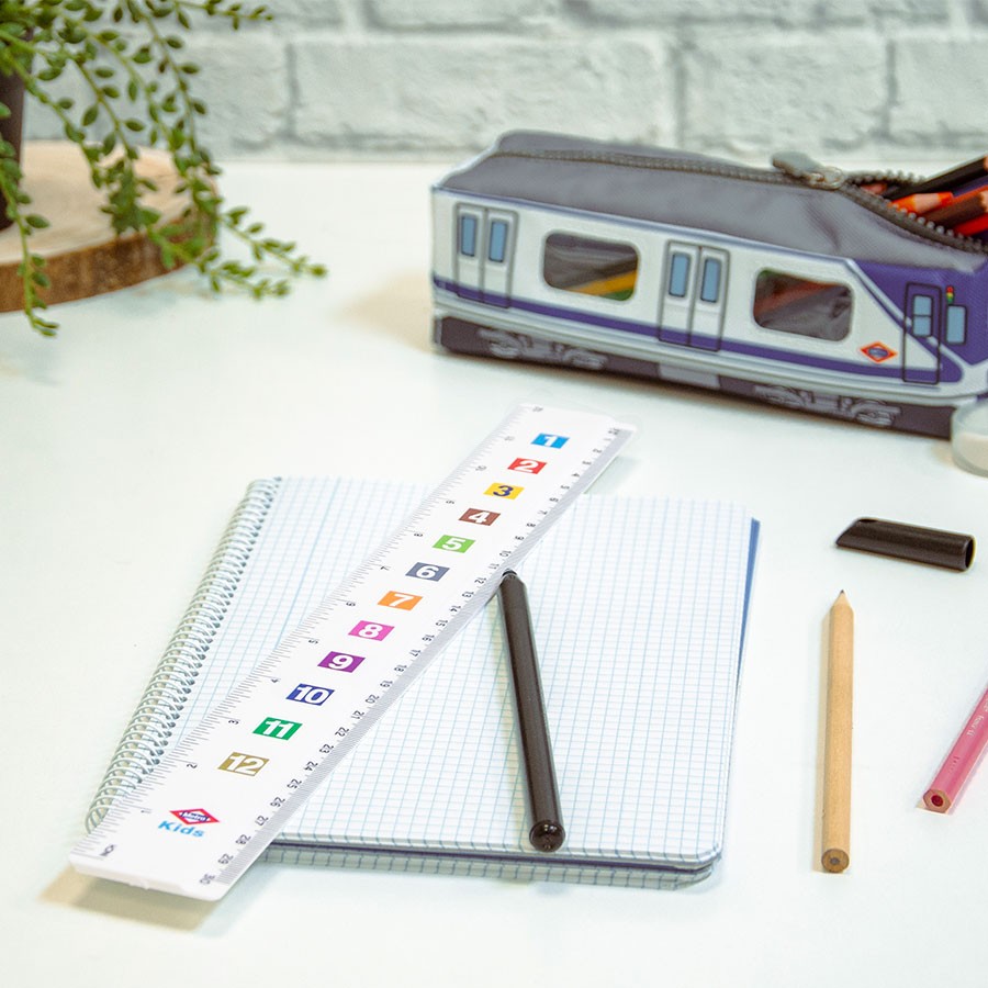 Estuche de metro, cuaderno cuadriculado, regla escolar y lápices sobre escritorio blanco