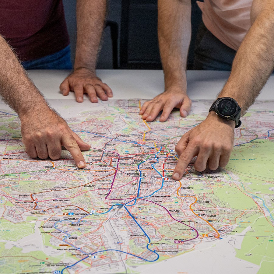 Manos señalando rutas en un mapa de ciudad sobre una mesa, planificación de viaje urbana