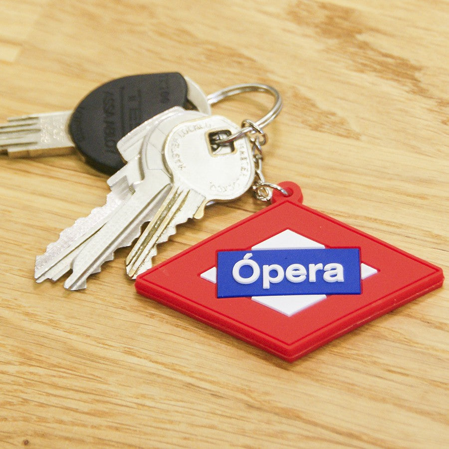Llavero de estación Ópera Metro Madrid junto a llaves sobre mesa de madera