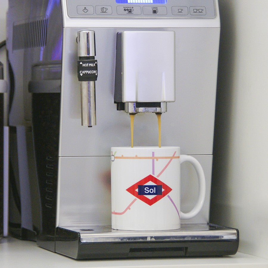 Cafetera automática sirviendo café en taza con diseño del Metro de Madrid y estación Sol