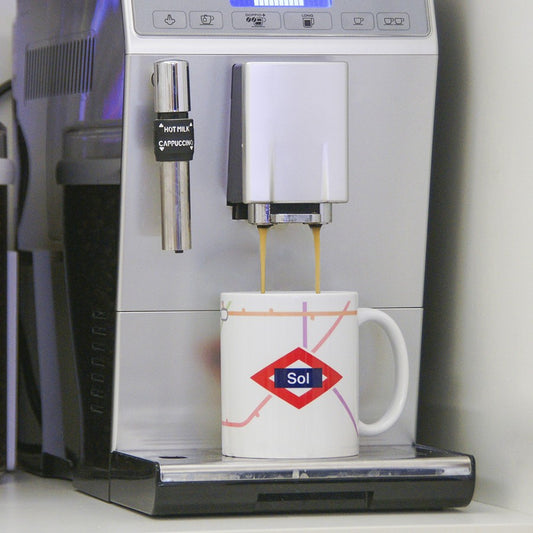 Cafetera automática sirviendo café en taza con diseño del Metro de Madrid y estación Sol