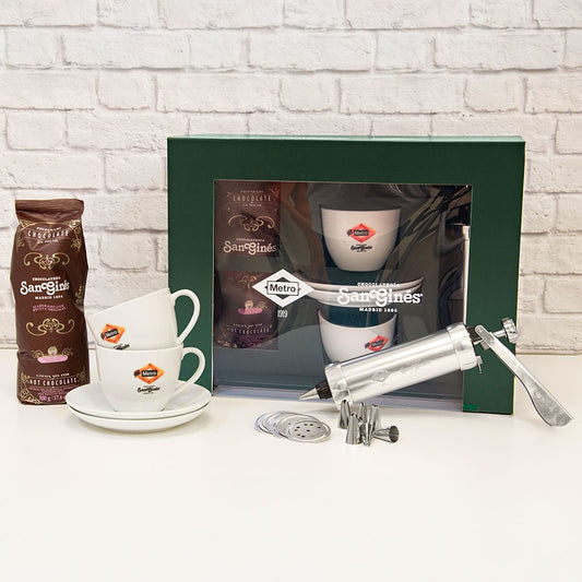 Set de chocolate San Ginés con dos tazas, manga pastelera y accesorios sobre fondo blanco