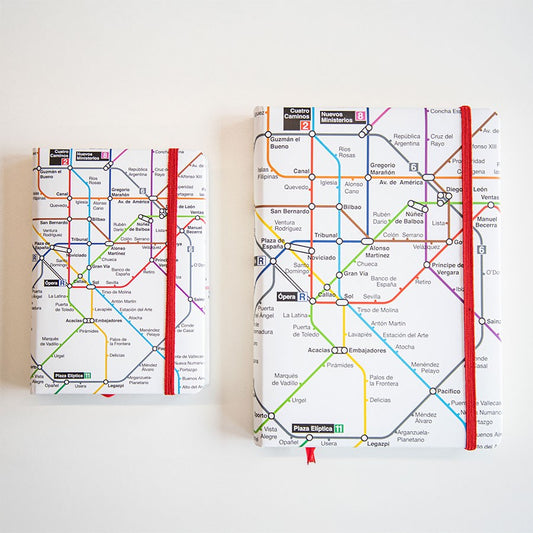 Cuadernos con cubierta de mapa del metro de Madrid y banda elástica roja sobre fondo blanco