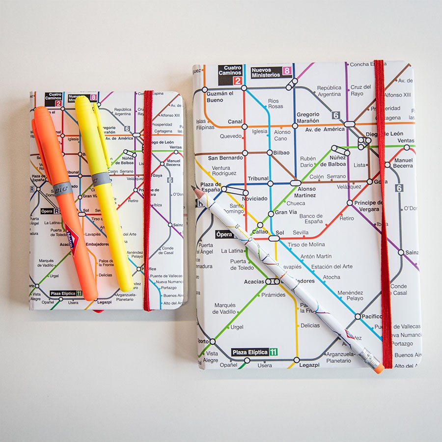 Cuadernos con diseño de mapa del metro de Madrid y bolígrafos BIC sobre fondo blanco