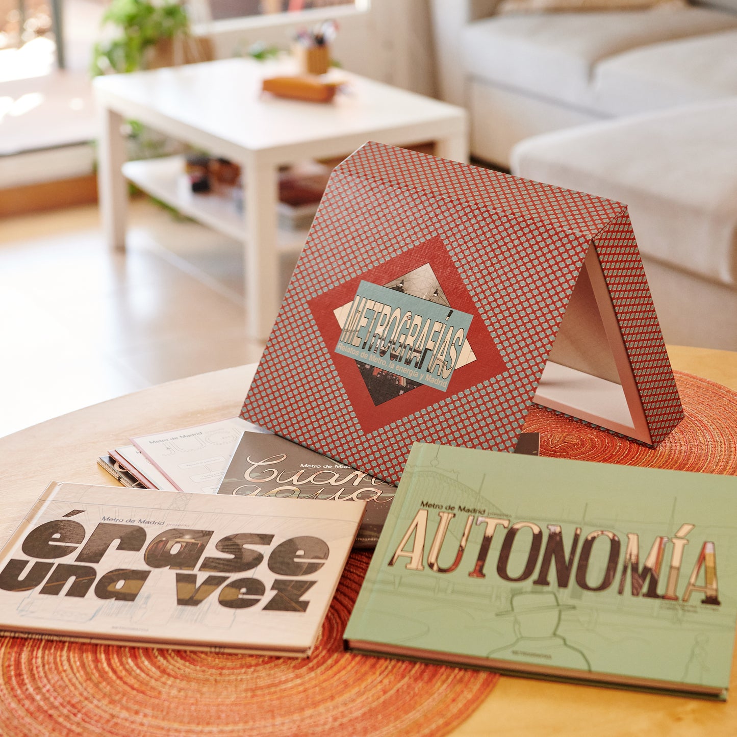 Libros de Metro de Madrid sobre mesa redonda en sala luminosa, títulos Érase una vez y Autonomía.