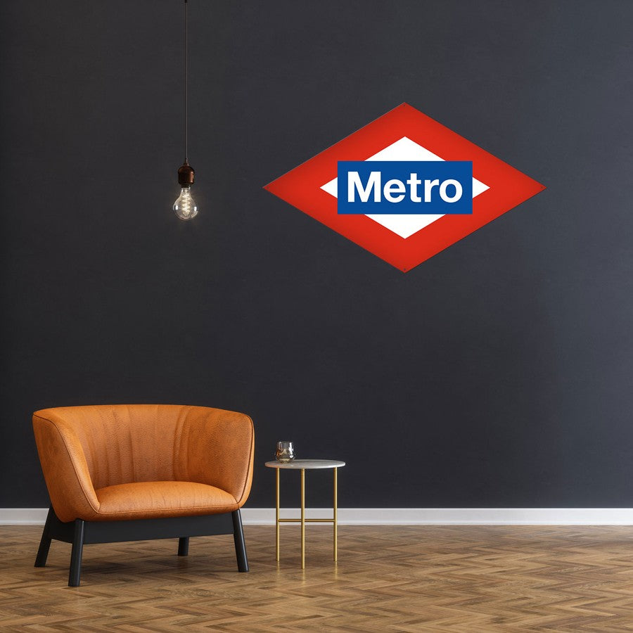 Sala moderna con sillón naranja, mesa auxiliar y logo Metro Madrid en pared gris.