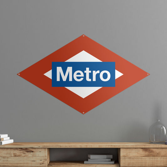 Letrero del Metro de Madrid colgado en pared gris, decoración urbana interior.