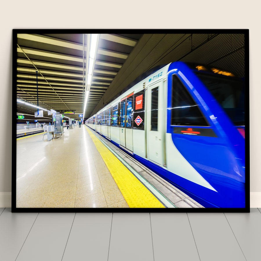 Fotografía de un tren azul moderno en una estación de metro iluminada y vacía.