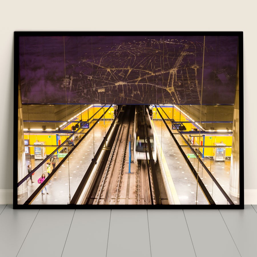 Fotografía de estación de metro moderna con paredes amarillas y tren en movimiento.