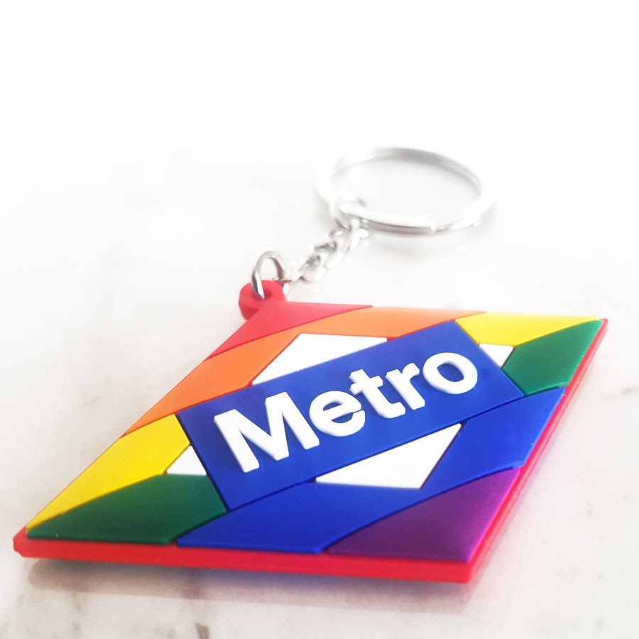 Llavero de goma cuadrado con colores arcoíris y la palabra Metro en fondo blanco.