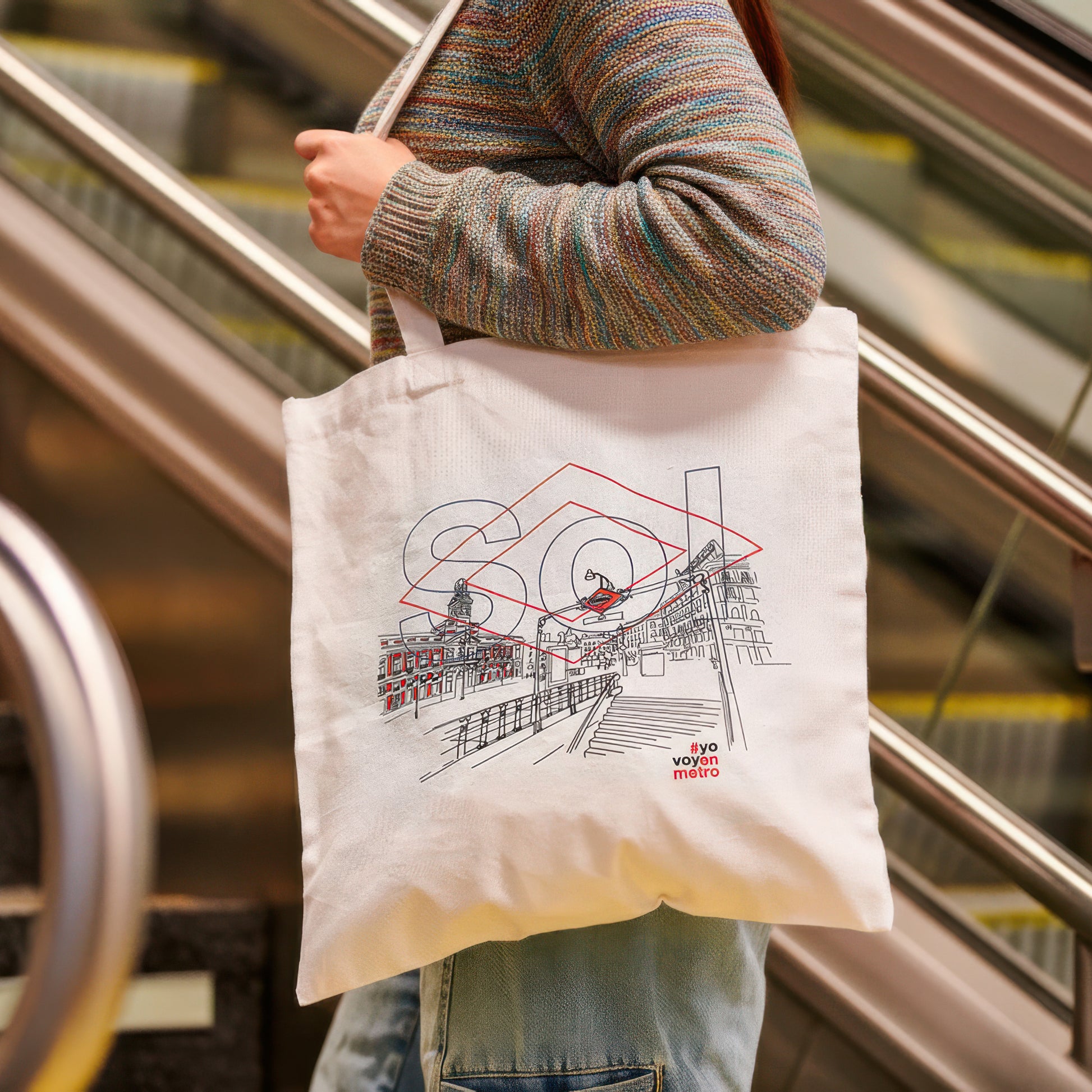Bolsa de tela con ilustración de la Puerta del Sol y texto #yovoyenmetro, escalera mecánica