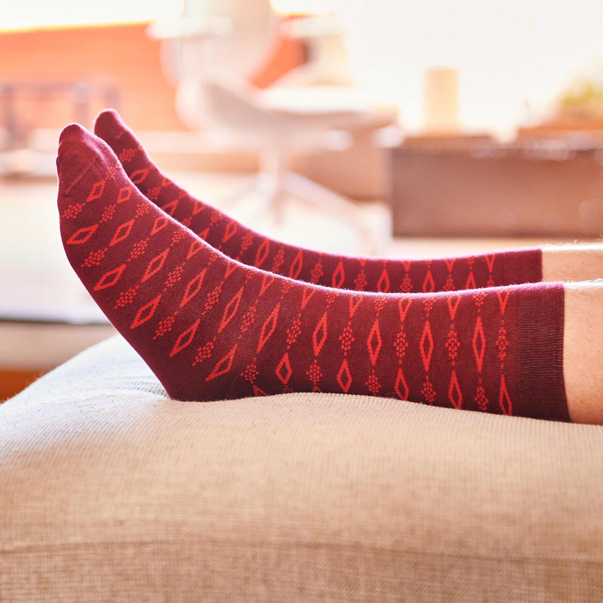 Calcetines rojos con patrón geométrico sobre sofá en ambiente luminoso y moderno
