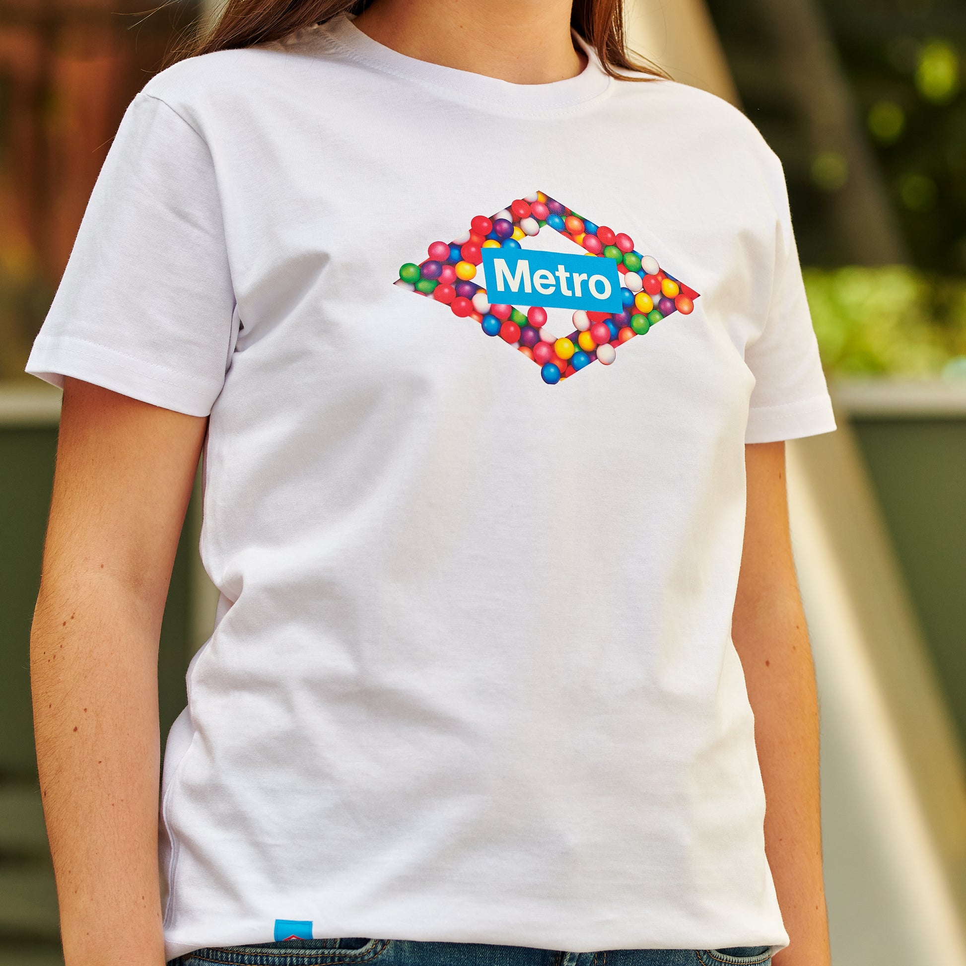 Camiseta blanca con logotipo de Metro formado por esferas de colores, moda urbana.