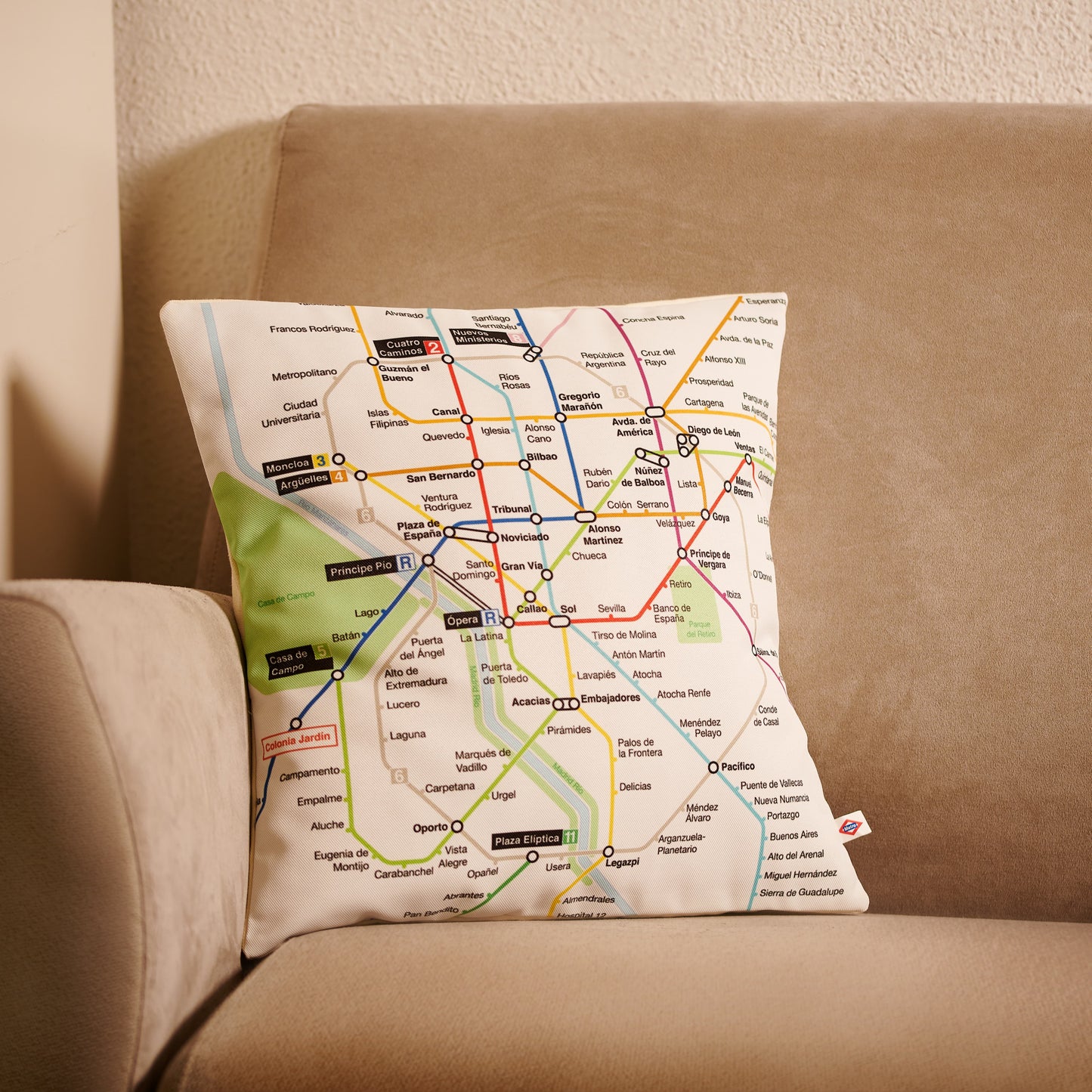 Cojín con diseño de mapa del metro de Madrid sobre un sofá beige en sala de estar