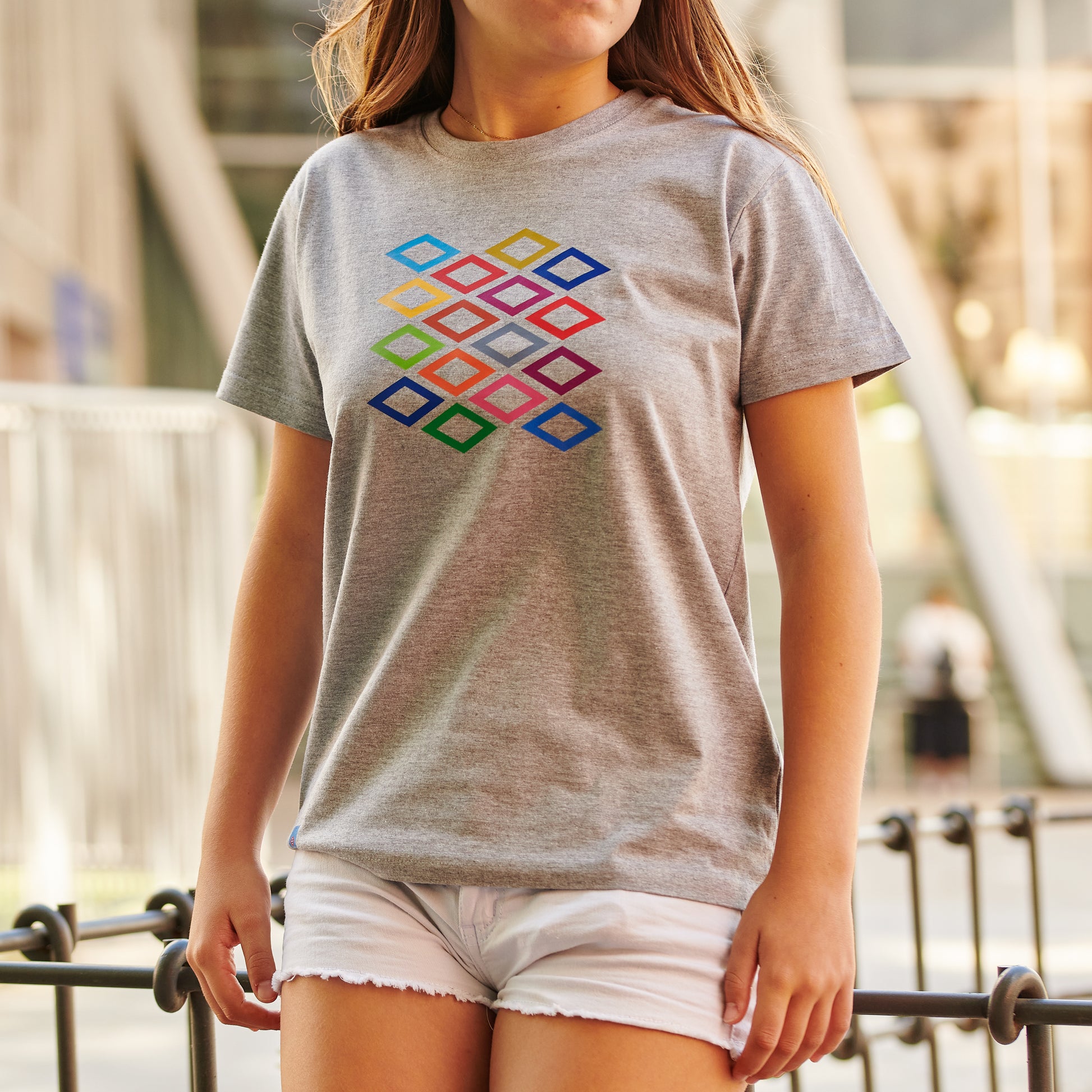 Mujer con camiseta gris de rombos coloridos y shorts blancos al aire libre