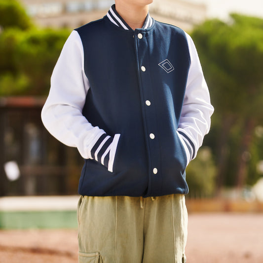 Chico con chaqueta varsity azul marino y blanca, al aire libre, moda juvenil urbana