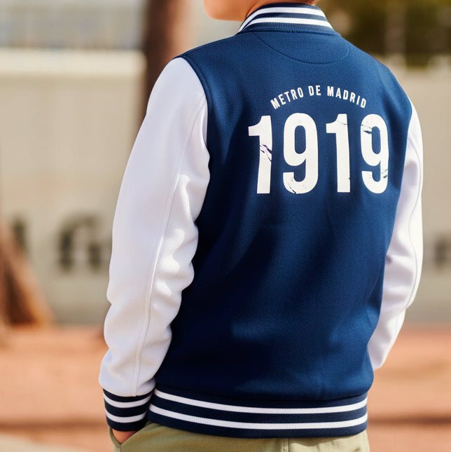 Chamarra varsity azul con mangas blancas, texto 'Metro de Madrid 1919' en la espalda