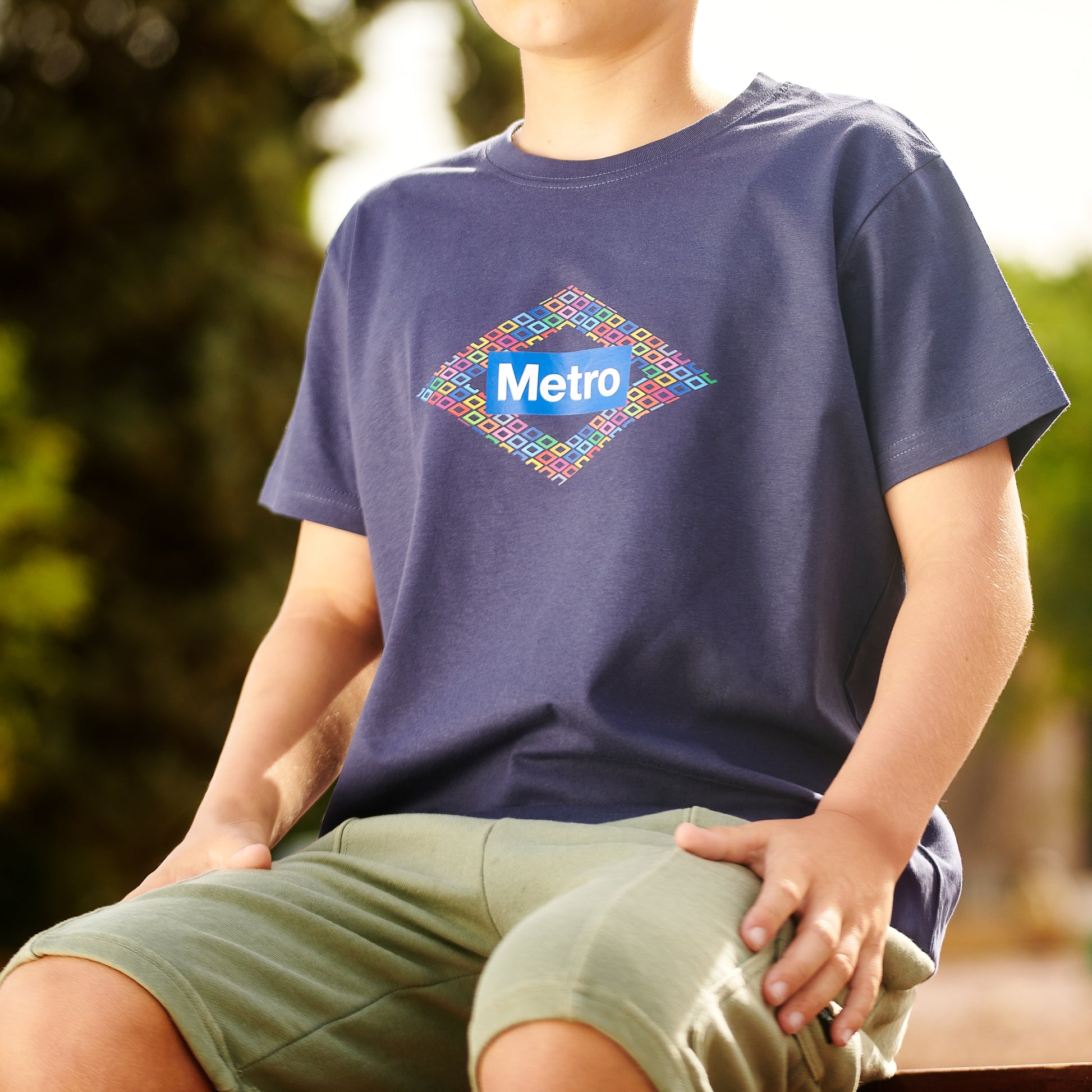 Niño con camiseta azul Metro, logo colorido al aire libre, ropa casual infantil.