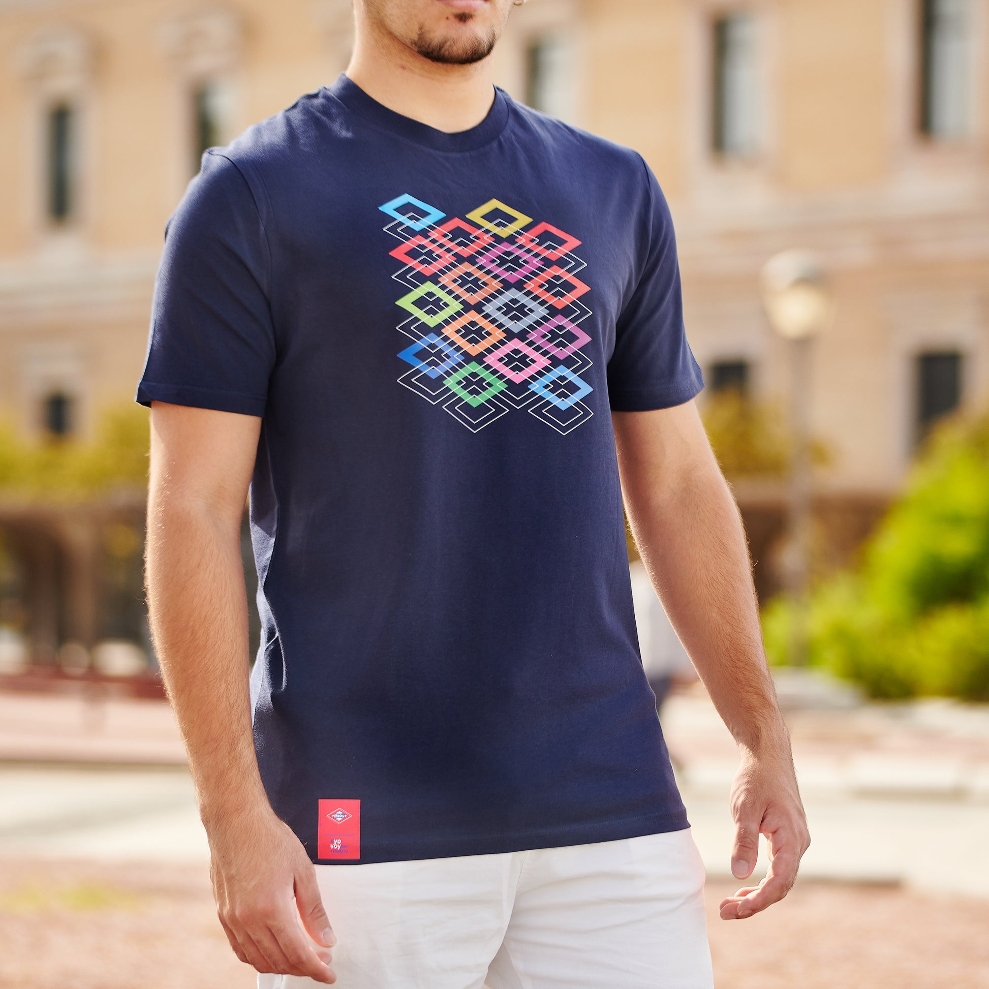 Hombre con camiseta azul marino de diseño geométrico colorido al aire libre