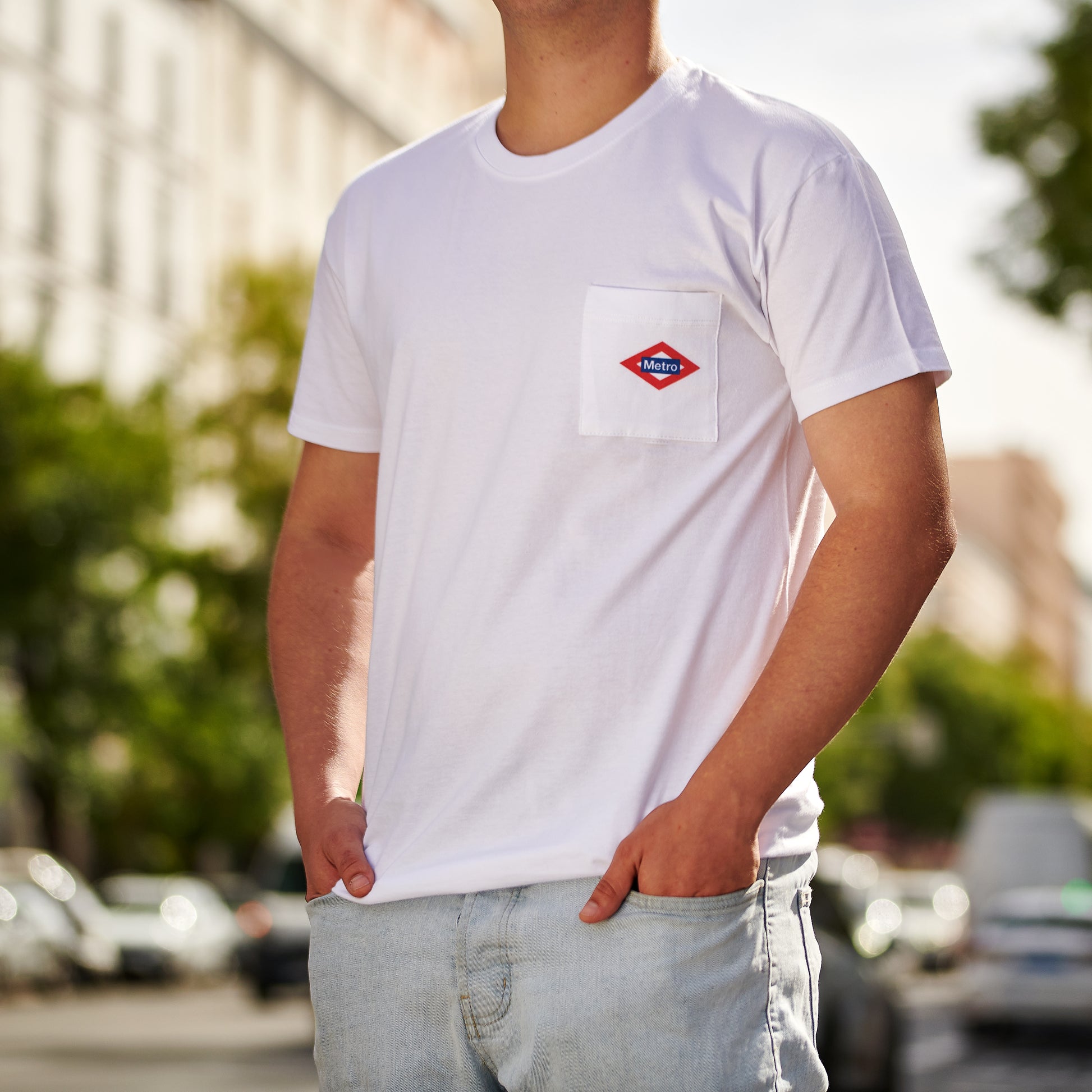 Hombre con camiseta blanca de metro Madrid y jeans claros en calle urbana soleada