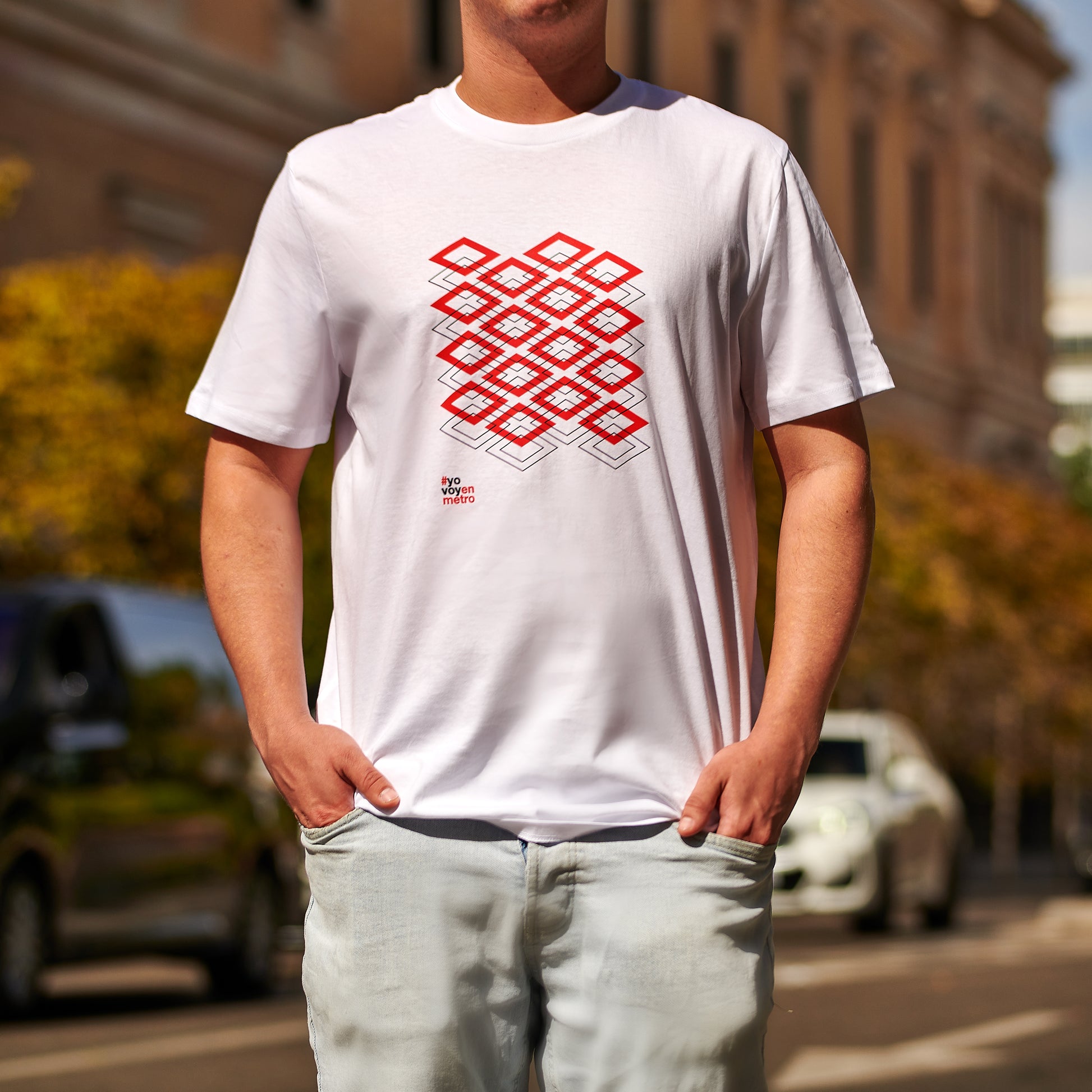 Hombre con camiseta blanca de estampado geométrico rojo en la calle, moda urbana.
