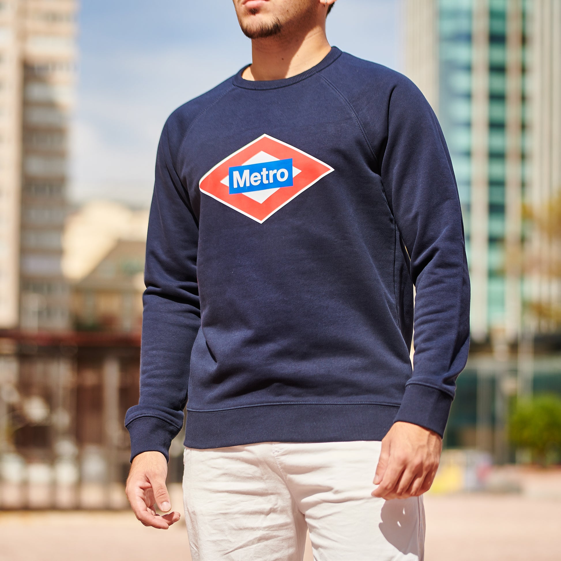 Hombre con sudadera azul Metro Madrid al aire libre, fondo urbano y edificios modernos