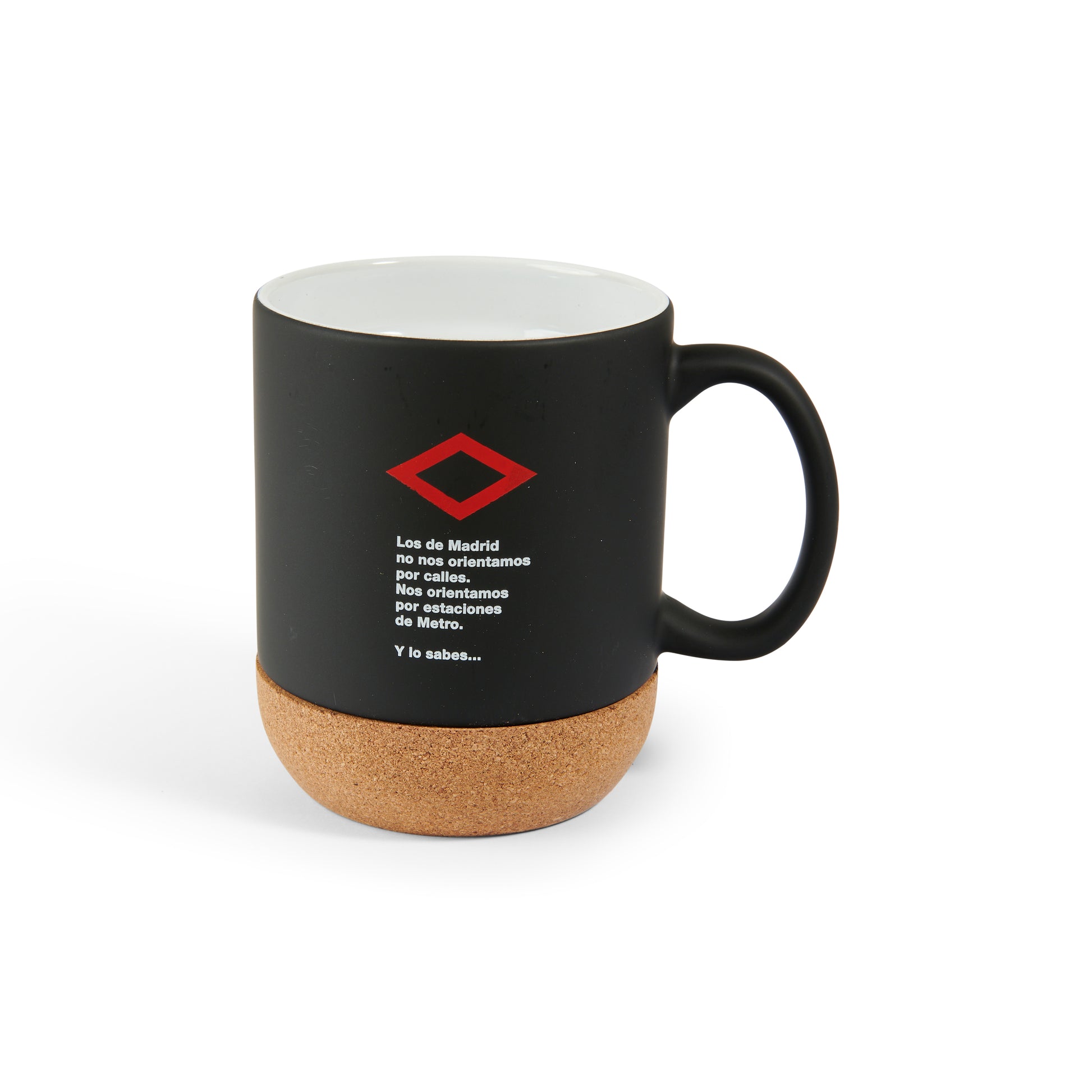 Taza negra con base de corcho y texto sobre el Metro de Madrid con logotipo rojo.